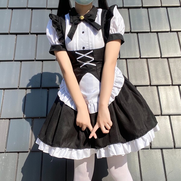 A woman wears a black and white gothic lolita maid dress with ruffles, buttons, and a bow tie, perfect for halloween costumes...