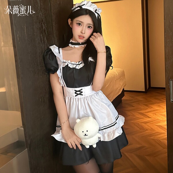 A woman wearing a black and white maid costume holding a plush bear, ideal for cosplay and role play.