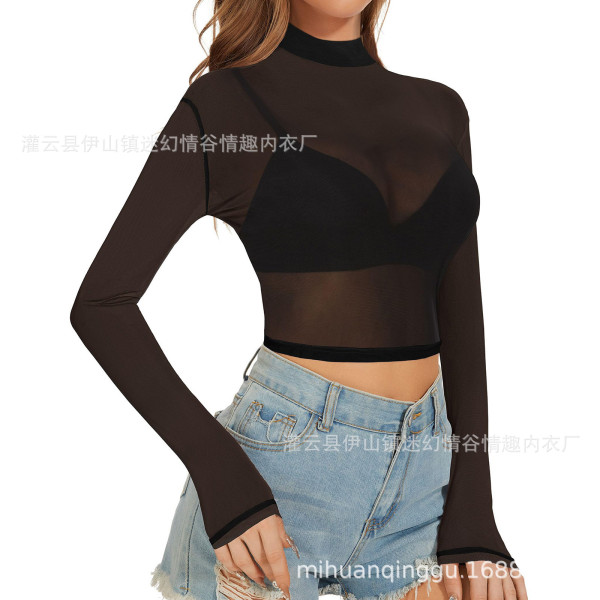 Woman wearing a black sheer mesh long sleeve crop top paired with blue jeans, showcasing a bold and confident style.