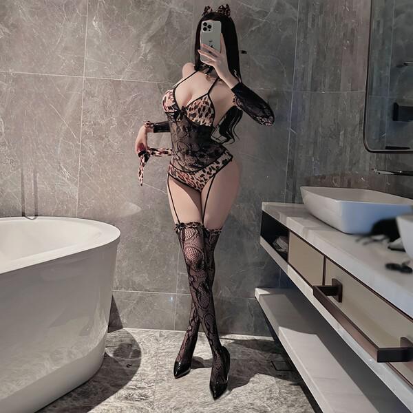 Woman wearing catwoman bodysuit costume with sexy leopard print, lace details, and thigh-high stockings in a modern bathroom.