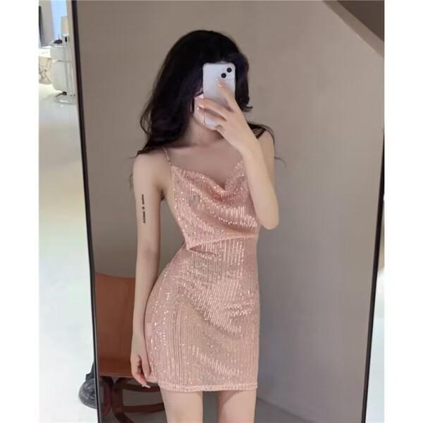 Woman in mirror wearing a shiny pink sequin mini dress with thin straps and a draped neckline.