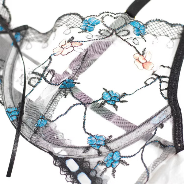 Close-up of embroidered garter belt with blue flowers, steel ring detail, and sheer lace in sexy womens lingerie set.