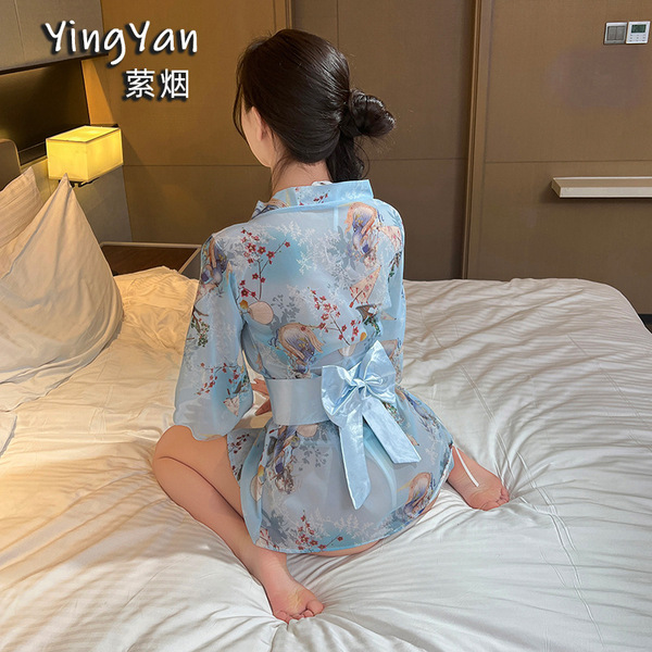 A woman sits on a bed wearing a light blue japanese-style lace kimono set, featuring a sheer robe with floral patterns and a ...