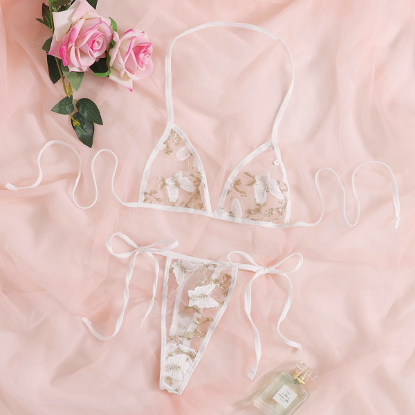 White lace bra and thong set with floral embroidery, elegant bridal lingerie on pink fabric with roses.