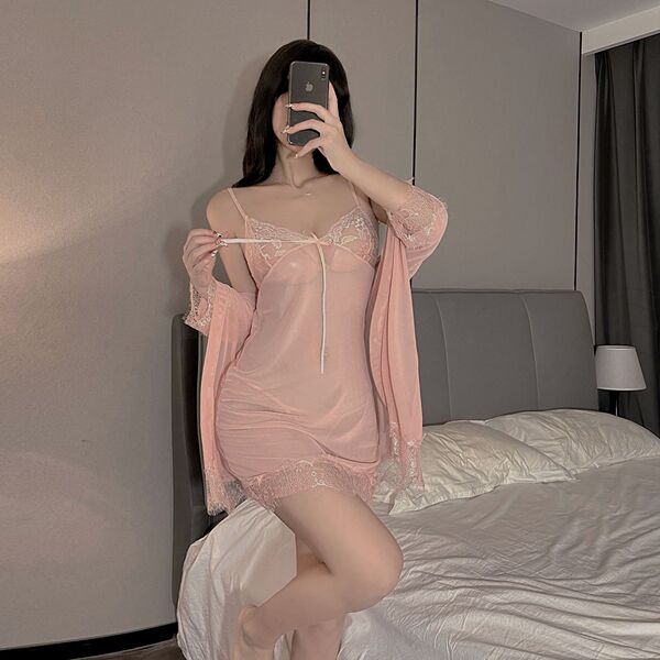 Woman in pink lace-trimmed sheer slip dress with matching robe, posing on bed — plus size sexy lingerie set.