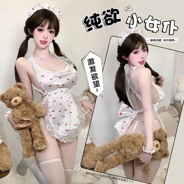 A woman poses in a white lace maid outfit with red cherry patterns, holding a teddy bear. the design features playful element...