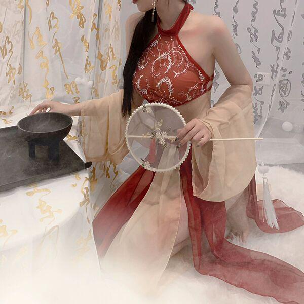 A woman elegantly poses with a traditional fan, wearing a luxurious red and beige costume inspired by classic attire. the des...