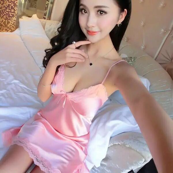 A woman poses with a pink silky cami set featuring lace details, ideal for sleepwear or loungewear. the outfit showcases a ...