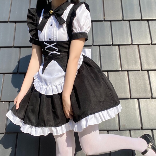 A woman wearing a black and white gothic lolita maid dress with ruffles, corset, and bow tie, perfect for halloween costumes.