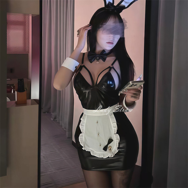 Woman wearing black bunny girl cosplay costume with white apron, bow tie, and ears, holding phone in mirror selfie.