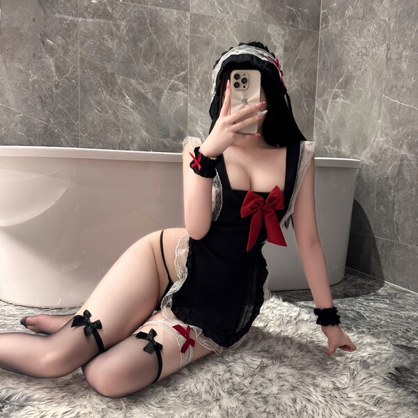 A woman poses in a maid costume set featuring a black apron with red bows, lace details, and stockings, capturing a playful b...