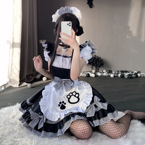 A person wearing a black and white maid costume with cat paw designs, sitting on a rug indoors. the outfit features ruffles a...