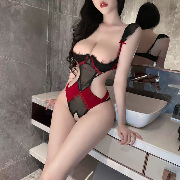 Woman wearing red and black cherry romance lingerie set with sheer bodysuit in modern bathroom setting.
