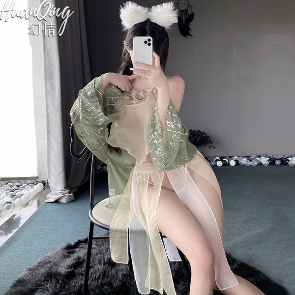 A woman poses with a smartphone, wearing a vintage floral lace chemise set. the outfit features a sheer design and fluffy bun...