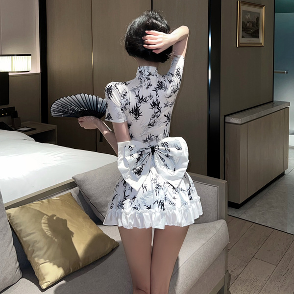 A woman stands facing away from the camera, wearing a white chinese new year dress inspired by red silk. the dress features a...