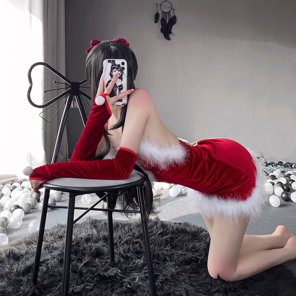 A person poses playfully on a chair wearing a festive christmas-themed sleepwear set, featuring a red mini skirt with white f...