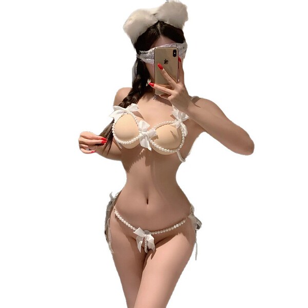 Woman modeling elegant pearl-embellished lingerie set with open-cup bra and matching thong, luxury sensual nightwear.