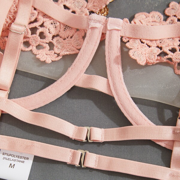 Close-up of pink lace lingerie straps with adjustable buckles and floral embroidery details.