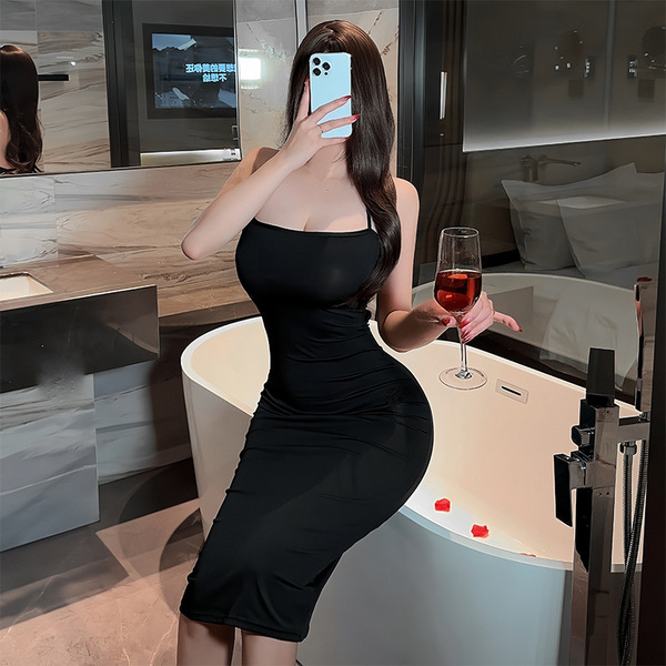 A woman poses in a bathroom wearing a black dress, holding a glass of wine, showcasing elegant evening attire.