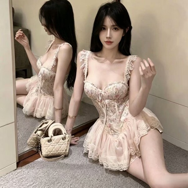 Woman wearing floral print sweet corset mini dress with built-in pads and waist-cinching design, posing beside mirror.