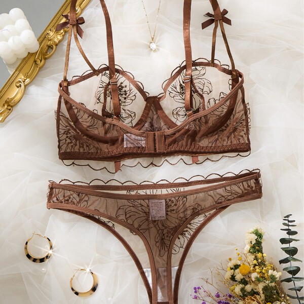 Brown french luxury lace lingerie set with floral embroidery, sheer cups, bow straps, and matching thong on white tulle.