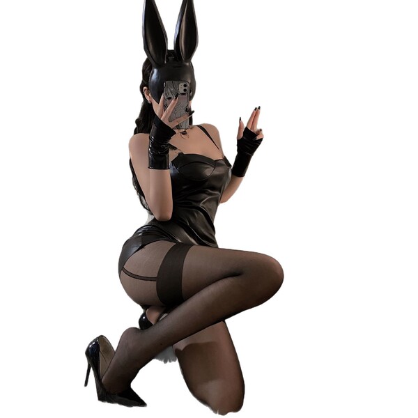 Woman in black pvc bunny girl outfit with ears, gloves, and stockings, posing seductively for nightclub or roleplay.