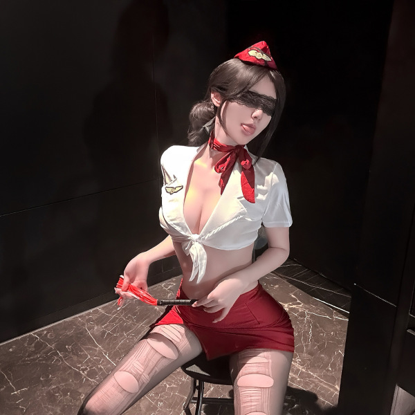 Woman in golden night air hostess lingerie set with sheer mesh, high-waisted skirt, and red accessories.
