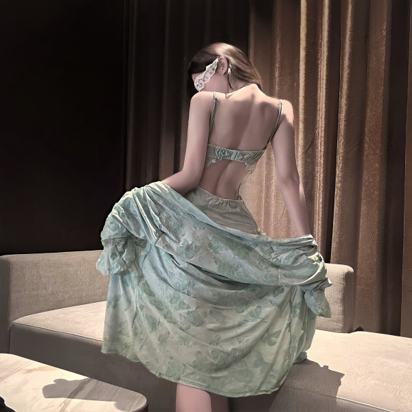Woman in elegant green lace lingerie set, featuring silk-feel chemise and garter belt, posed on sofa.