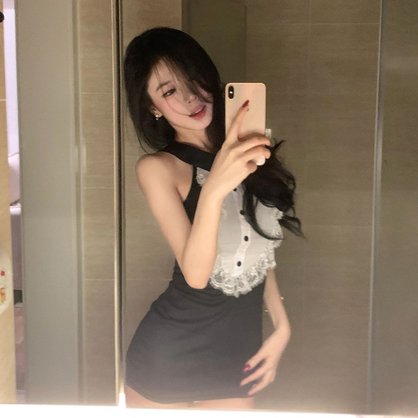 A woman poses in a black and white dress featuring lace details and heart cutouts, capturing a selfie in a mirror. the outfit...