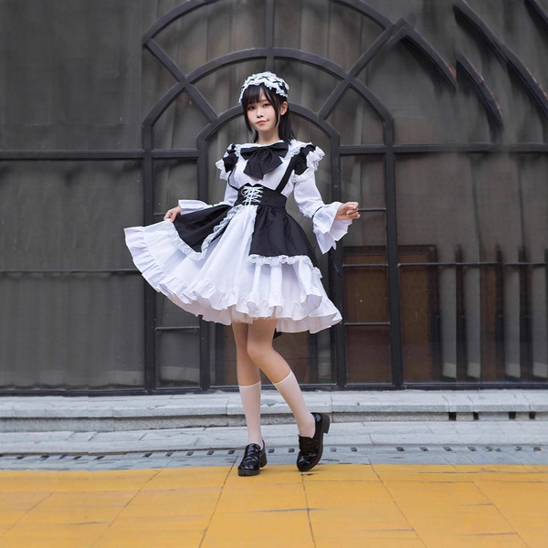 A stylish individual wears a black and white gothic lolita maid dress, perfect for halloween and cosplay events. the outfit f...