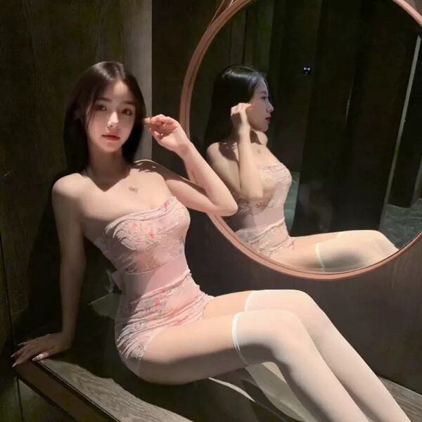 A woman poses elegantly in a sheer lace bodysuit set, featuring an embroidered floral print and backless design, inspired by ...
