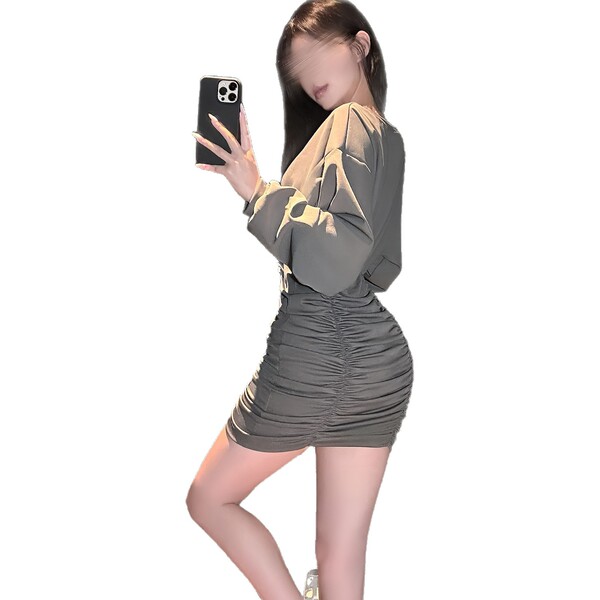 Woman in a flirty, ruffled bodycon mini dress with a waist-cinching design, taking a selfie.