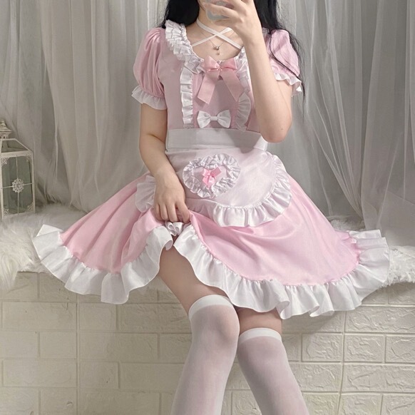 A person wearing a japanese anime maid costume, featuring a pink and white dress with ruffles and bows, perfect for restauran...