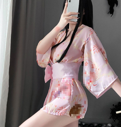 A woman poses with a smartphone, wearing a pink japanese cherry blossom-themed kimono-style sleepwear set. the outfit feature...
