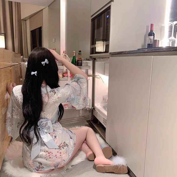 A woman sits on the floor wearing a japanese-style couples pajama set, featuring a floral kimono with butterfly accents and b...