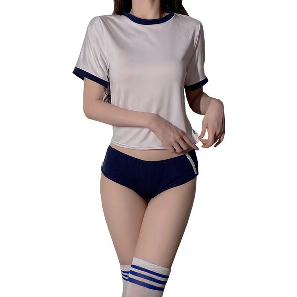 A woman models a japanese gymnastics outfit, featuring a beige crop top with navy trim and matching navy shorts, paired with ...