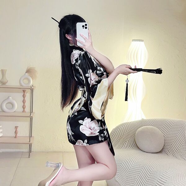 A woman poses in a japanese kimono lingerie set featuring a floral print and dramatic sleeves, holding a fan accessory.