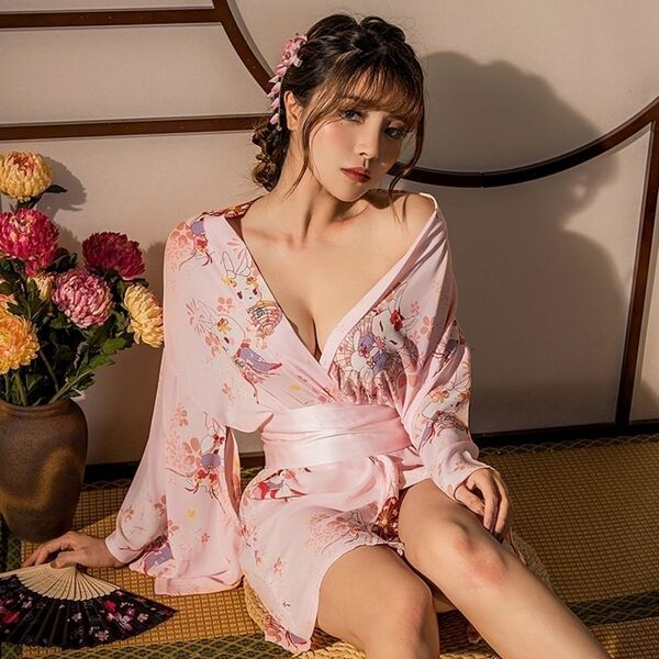 A woman wears a delicate pink japanese kimono-style sleepwear set, featuring floral patterns and a deep v-neckline, perfect f...
