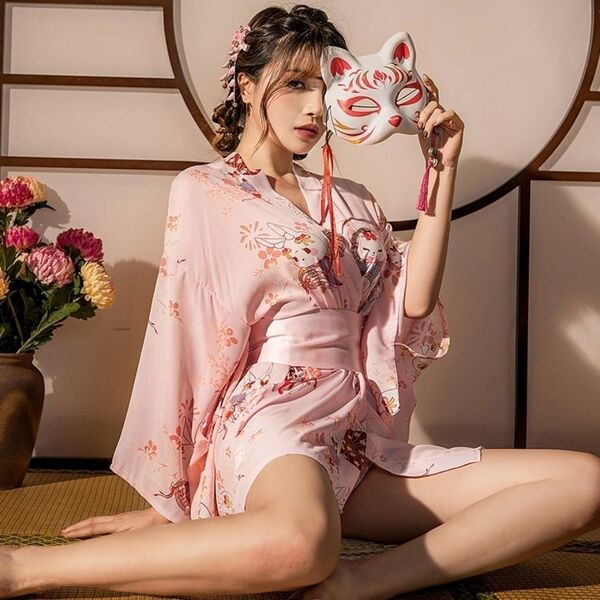A woman wears a pink japanese kimono-style sleepwear set featuring floral patterns, paired with a fox mask accessory, creatin...