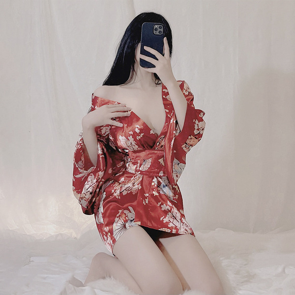A woman poses in a red japanese-style kimono-inspired lingerie set, featuring a deep v neckline and flowing sleeves, creating...