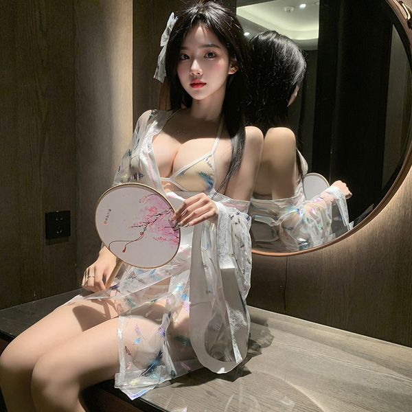 A woman poses elegantly in a sheer kimono-inspired bodysuit, featuring delicate lace detailing and a waist cinching design. t...