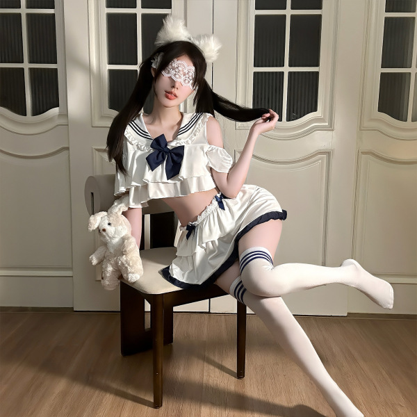 Model wearing jinxiao jk style flirty lingerie skirt with pleated mini design, white top, navy bow, and thigh-high socks.