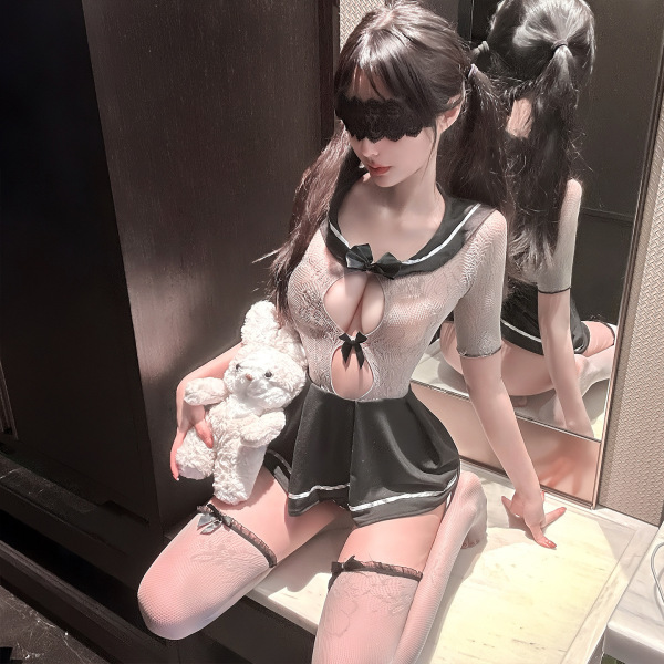 Woman in jinxiao jk sailor suit lingerie, sheer mesh bodysuit with black trim, holding teddy bear, seated by mirror.