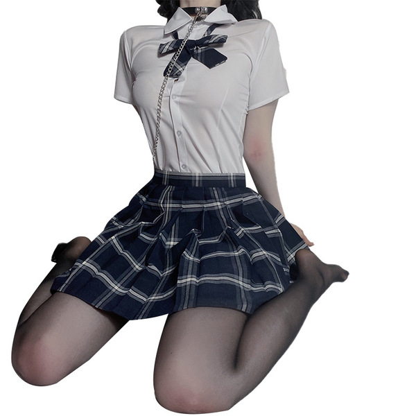A woman wearing a cute schoolgirl uniform, featuring a plaid skirt and matching blouse with a bow tie, paired with stockings.