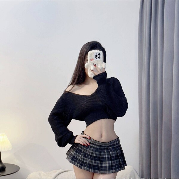A woman poses with a phone featuring a cute face design, wearing a black low-neck sweater and a plaid mini skirt. the outfit ...