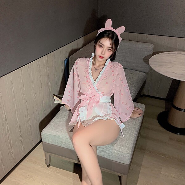 A woman wears a pink kimono-style lingerie set with bunny ears, featuring delicate patterns and ruffles, perfect for intimate...