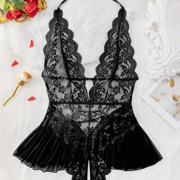 Luxury black lace bodysuit with sheer floral detailing and scalloped edges, styled on white fur with rose petals.