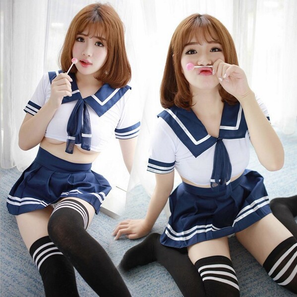 Two women wearing matching sailor-style outfits with bows, sailor skirts, and striped stockings pose playfully indoors.