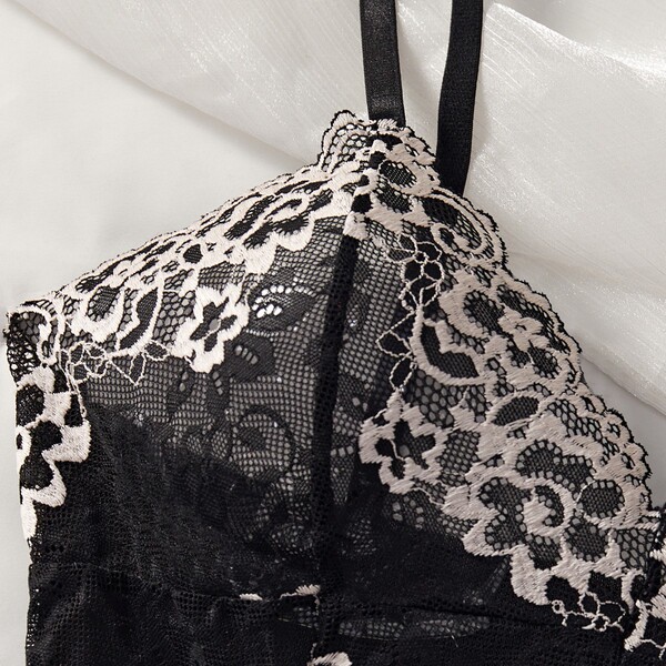 Close-up of black lace mesh bodysuit with floral detailing and sheer fabric, perfect for sensual sleepwear or intimate linger...