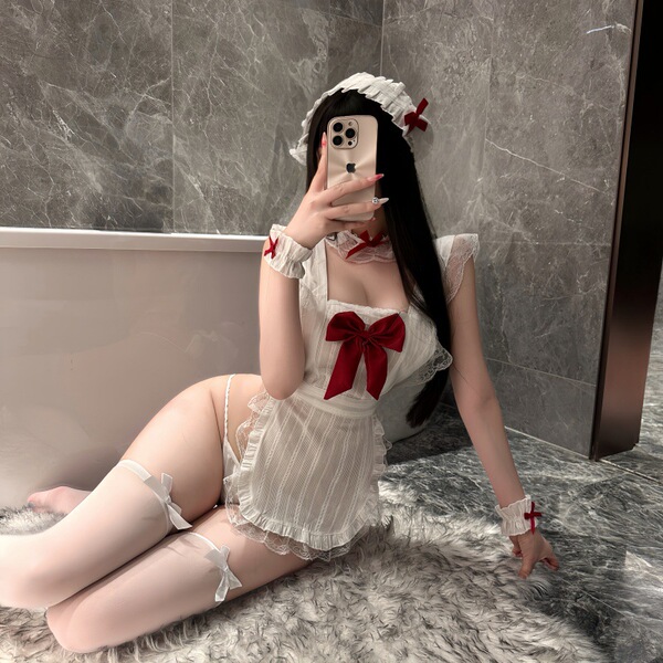 A woman poses in a lace nightwear set featuring ruffled hem details, a large red bow, and sheer stockings, creating a flirty ...